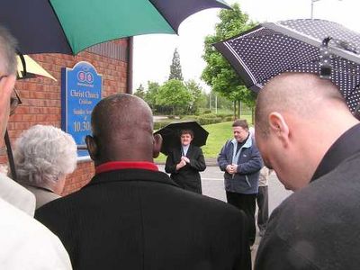 New Christ Church sign dedication prayers in the rain
